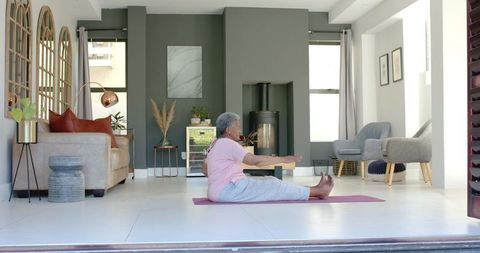Senior African Woman Practicing Seated Yoga Stretch in Bright Modern Living Room