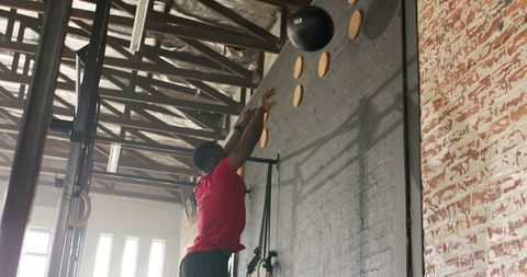 Athlete performing wall ball exercise in industrial gym