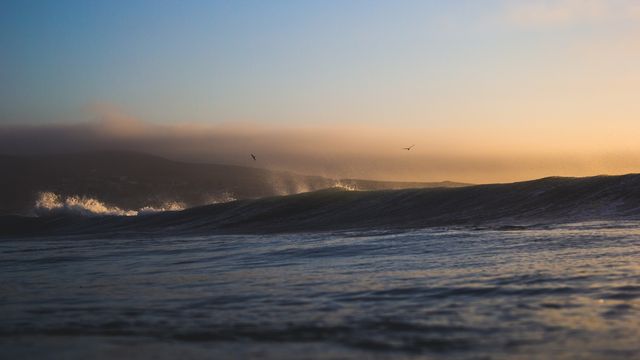 Ocean Waves at Sunset with Misty Hills - Download Free Stock Photos Pikwizard.com