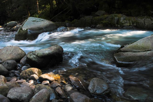 This scenic scene features a tranquil mountain stream flowing over rocks through a forest area. Ideal for nature blogs, travel websites, wellness retreats, and environmental articles.