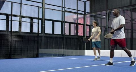 Diverse Male Paddle Players on Indoor Court Ready for Match