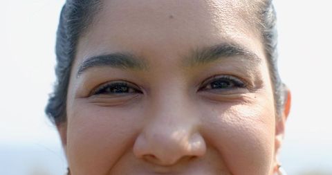 Middle-aged woman smiling close-up showing natural skin texture, earring, warm sunlight