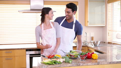 Couple Smiling While Preparing Fresh Salad Together