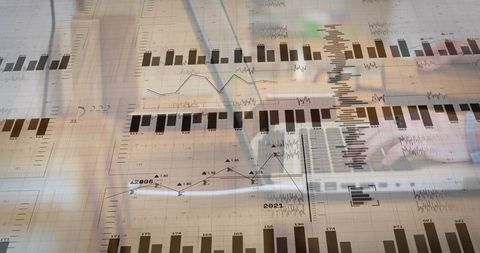 Analyst Working with Financial Charts and Laptop Overlay Showing Market Data Trends