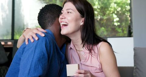 Happy Couple Embracing with Gift in Living Room