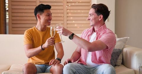 Diverse Gay Couple Toasting with Drinks at Home Joyful Bonding