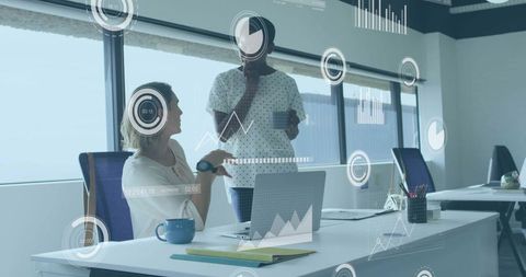 Women Wearing Headscarf Collaborating Over Digital Data Dashboards in Open-Plan Office