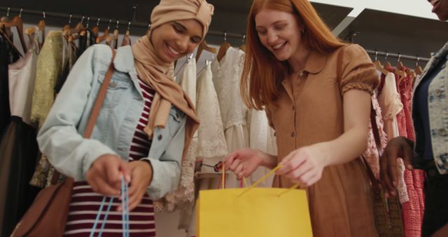 Women having fun shopping for clothes in a boutique. Great for use in advertisements related to fashion, retail, multicultural friendships, and lifestyle content.