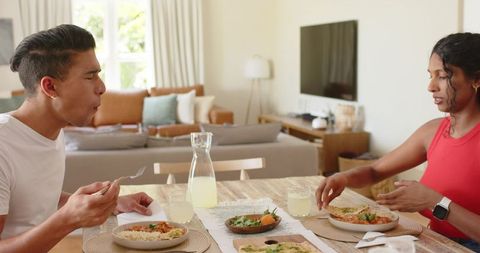 African american couple sharing healthy homemade meal and lemonade at sunlit dining table