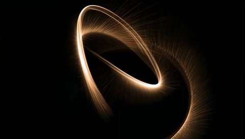 Glowing golden loop and ribbon swirling across dark field emitting radial sparks and halo