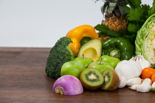 Close-up of various fresh fruits and vegetables spread on a wooden table. Ideal for use in articles about healthy eating, diet plans, nutrition, and recipes. Great for social media posts, grocery store advertisements, wellness blogs, and educational materials on healthy living.