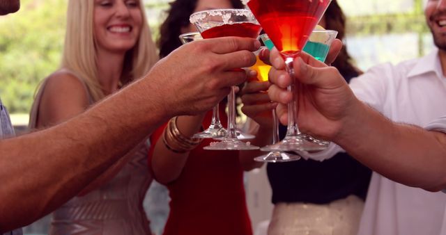 Group of friends toasting with vibrant cocktails. This image captures celebration and social interaction, perfect for promoting events, parties, social gatherings, and lifestyle content.