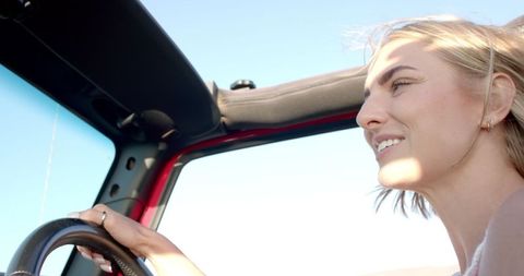 Joyful Woman Driving Convertible Under Clear Blue Sky