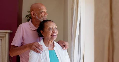 Senior Couple Relaxing at Home Gazing Peacefully Through Window