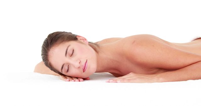 A young Caucasian woman is lying down peacefully, with copy space. Her serene expression suggests relaxation, in a spa or wellness setting.