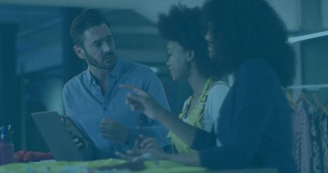 Creative team collaborating in design studio with tablet and swatches