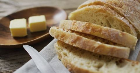Freshly baked bread slices with butter on rustic table