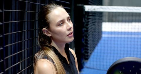 Female Athlete Resting Against Fence on Padel Court