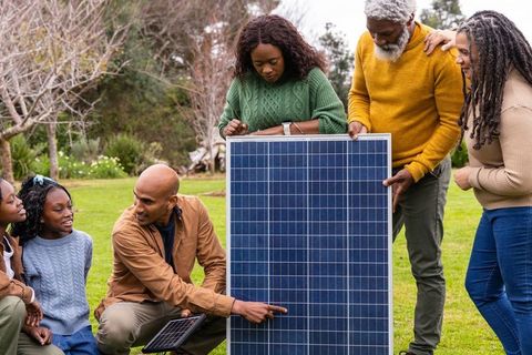 Multigenerational african american family demonstrating solar panel use outdoors