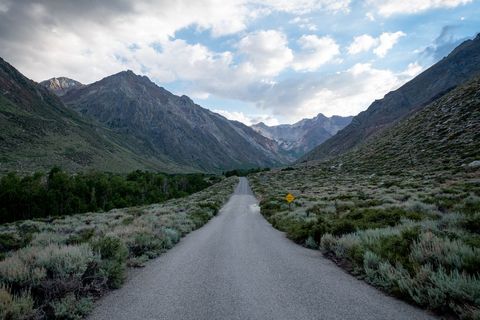 Deserted Mountain Road Stretching Through Vast Valley under Cloudy Sky