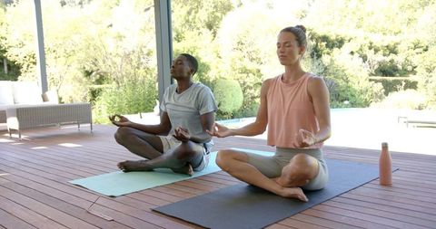 Mixed Race Couple Practicing Yoga Outdoors on Sunny Day