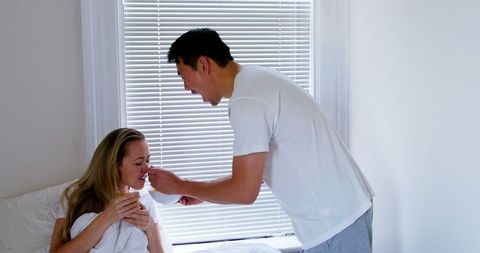Man Feeding Breakfast to Woman in Bright Bedroom