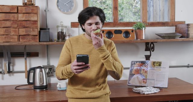 Young Man Eating Breakfast and Checking Phone in Modern Kitchen - Download Free Stock Images Pikwizard.com