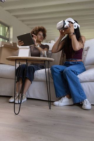 African american friends trying virtual reality headset while using tablet in living room
