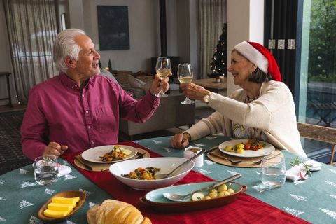 Senior couple celebrating christmas with wine in festive dining room