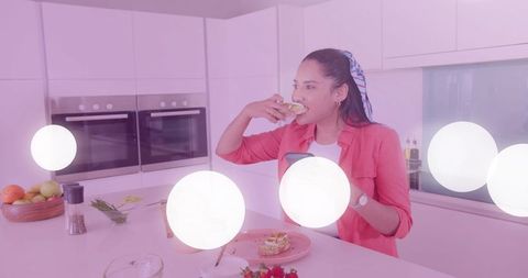 Indian Woman Enjoying Sandwich with Smartphone in Modern Kitchen