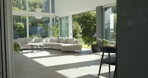 Sunlit modern living room showcasing beige l-shaped sectional, black coffee tables, garden view
