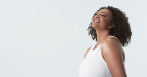 Joyful Plus Size Woman with Curly Hair Smiling Against White