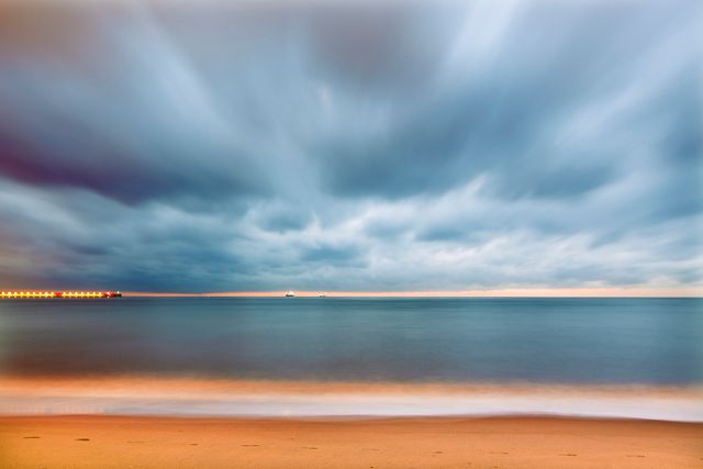 Serene Beach with Dramatic Cloudy Sky and Calm Sea at Sunrise - Download Free Stock Photos Pikwizard.com
