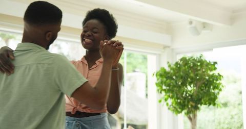 Joyful Couple Dancing Cheerfully Indoors in Sunlit Room