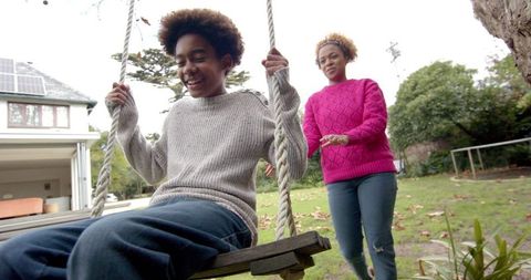 Mother and son enjoying time together on tree swing in garden