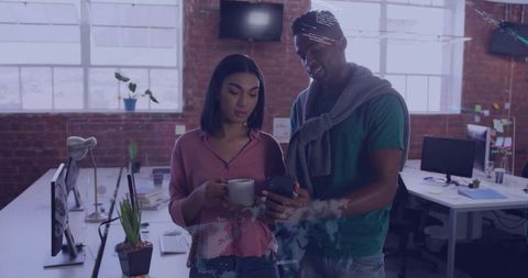 Coworkers collaborating over smartphone in modern industrial loft office