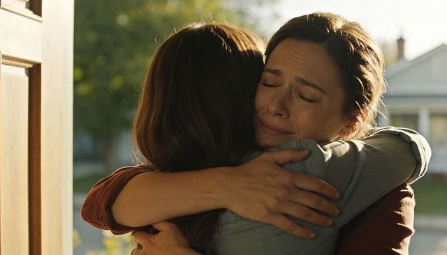 Women embracing in tearful reunion on sunlit front porch showing comfort and warmth