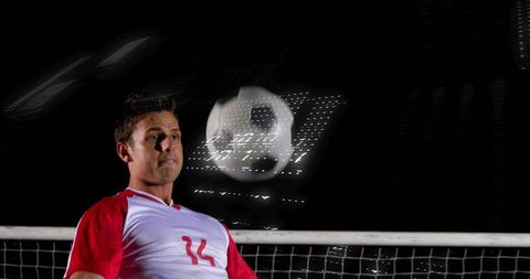 Football Player Heading Ball at Night Stadium