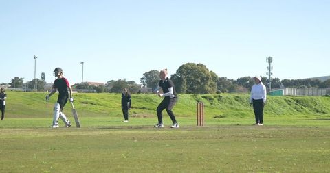 Women Playing Cricket on Outdoor Field with Wicketkeeper in Action