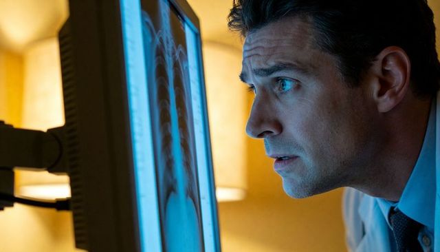 Intense clinician examining chest x-ray on monitor for lung diagnosis and radiology review