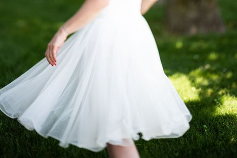 Woman Twirling in Elegant White Dress on Grassy Field