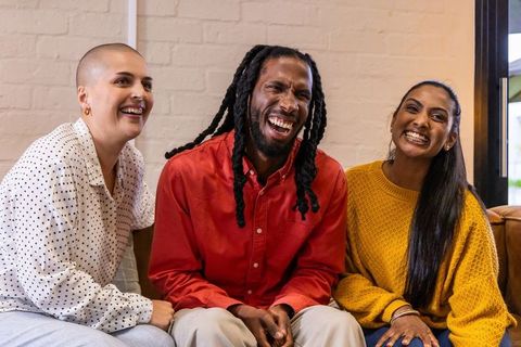 Diverse friends laughing on cozy sofa, casual lifestyle, joyful connection and warmth