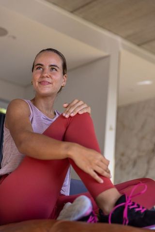 Relaxing young woman sitting on couch after workout in modern bright home