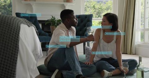 Couple sitting on floor clinking wine glasses in cozy living room with digital ui overlays