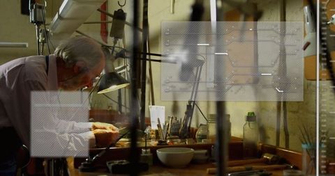 Skilled senior craftsman repairing watches in dimly lit workshop