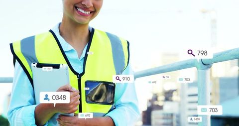 Smiling rooftop inspector wearing high-visibility vest holding tablet tracking construction data