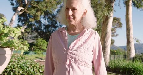 Senior Woman Enjoying Nature in Tranquil Garden with Pink Jacket
