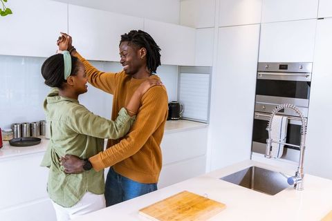African american couple dancing and embracing on kitchen island in bright modern home