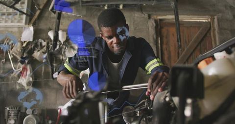 Mechanic tightening motorcycle engine with wrench in dim workshop with blue HUD overlay