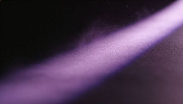 Narrow lavender light beam crossing dark textured surface with floating dust particles